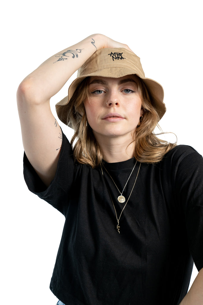 women with blond hair and a black shirt wearing a beige bucket hat