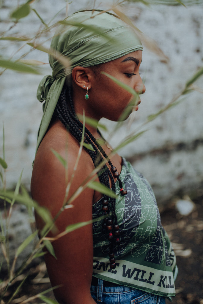 Black woman wearing a green Durag and a print African style bandana as a summer top