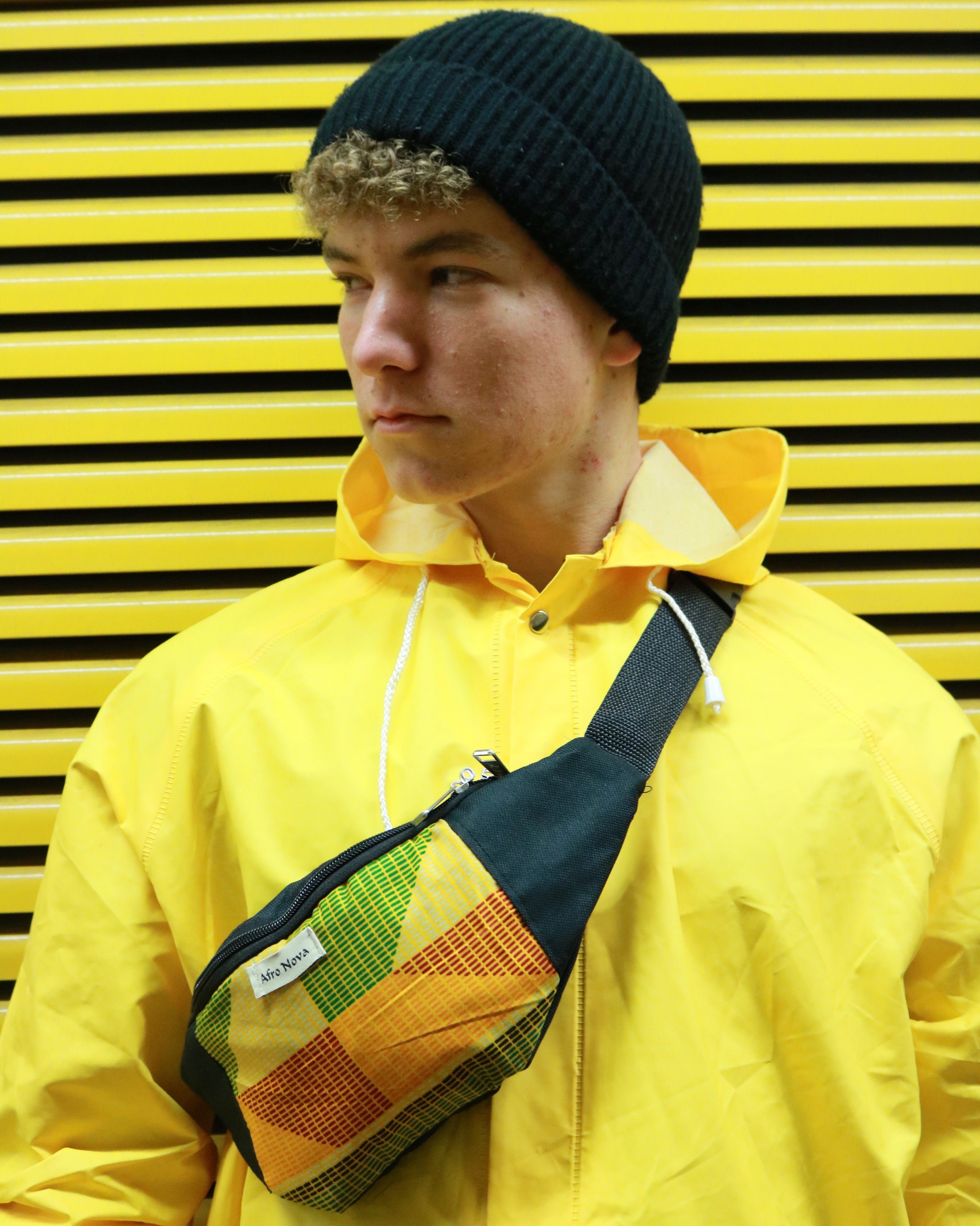 Bunte Bauchtasche für Festivals oder Reisen getragen von einem Mann mit gelber Regenjacke vor gelbem Hintergrund